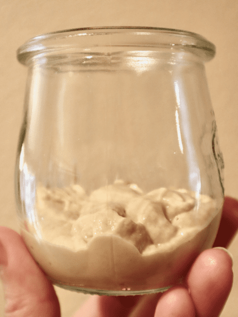 A small jar 1/3 filled with fresh sourdough starter.