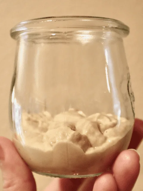 A small jar 1/3 filled with fresh sourdough starter.