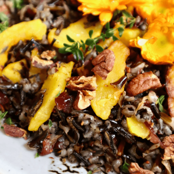 Close-up of the fluffy, black wild rice grains, golden delicata squash, juicy cranberries, toasted pecans, and fresh thyme.