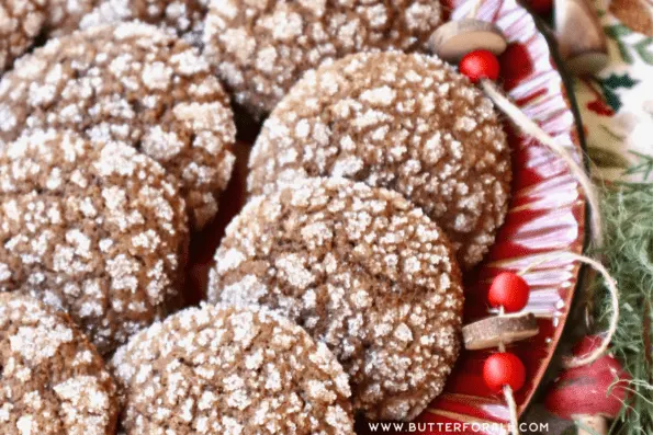 Brown and white crinkle cookies on a red platter with bead garland and greenery.