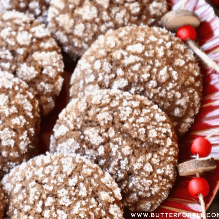 Brown and white crinkle cookies on a red platter with bead garland and greenery.