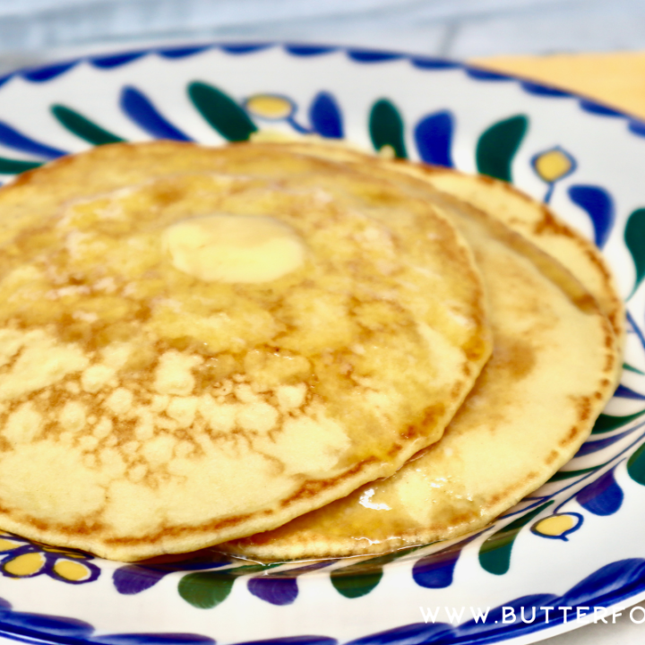 A decorative plate with a stack of golden-colored einkorn pancakes.