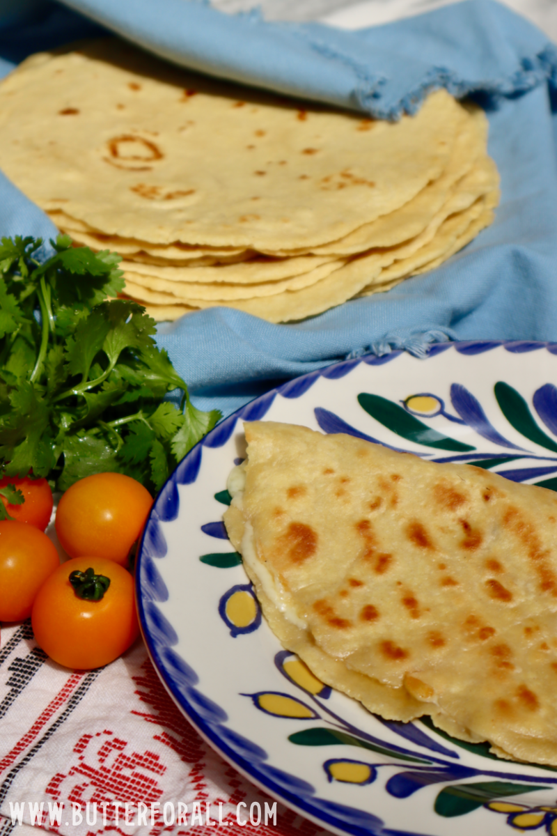 Crispy, golden einkorn sourdough tortillas hot off the griddle and stacked in a colorful napkin.