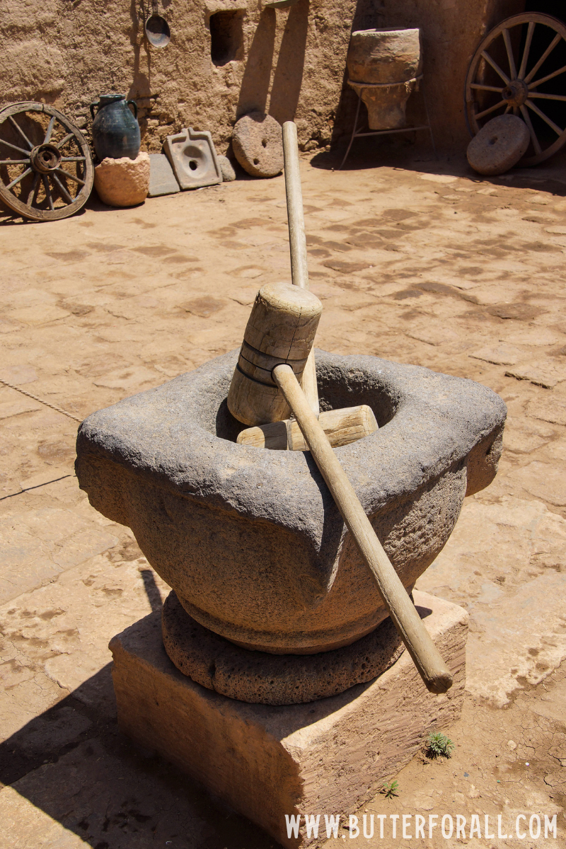 A tall stone grain grinder with hammer.