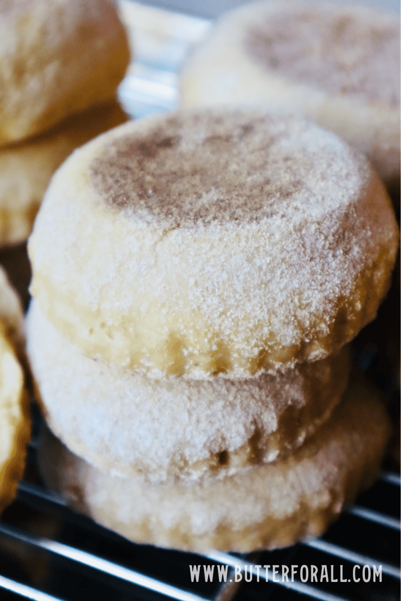 A stack of golden brown einkorn English muffins on a cooling rack