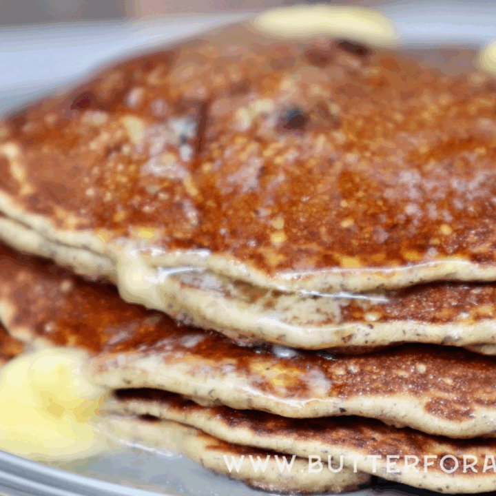 A golden brown stack of gluten-free pancakes with butter, melting, and dripping down the sides.