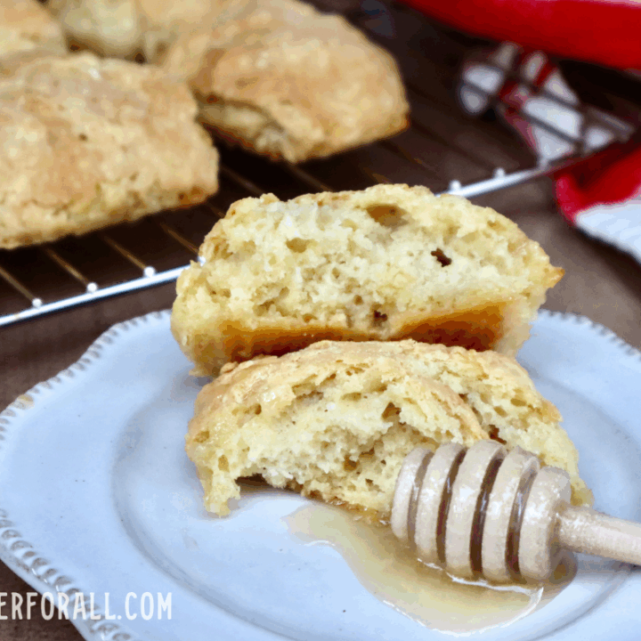 A golden einkorn sourdough biscuit with a honey covered honey dipper next to it.